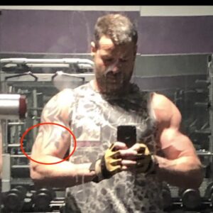 Michael lee francis in gym mirror selfie, mirror is dirty af, with tribal looking tats he probably got in the early 2000s when ppl did shit like that